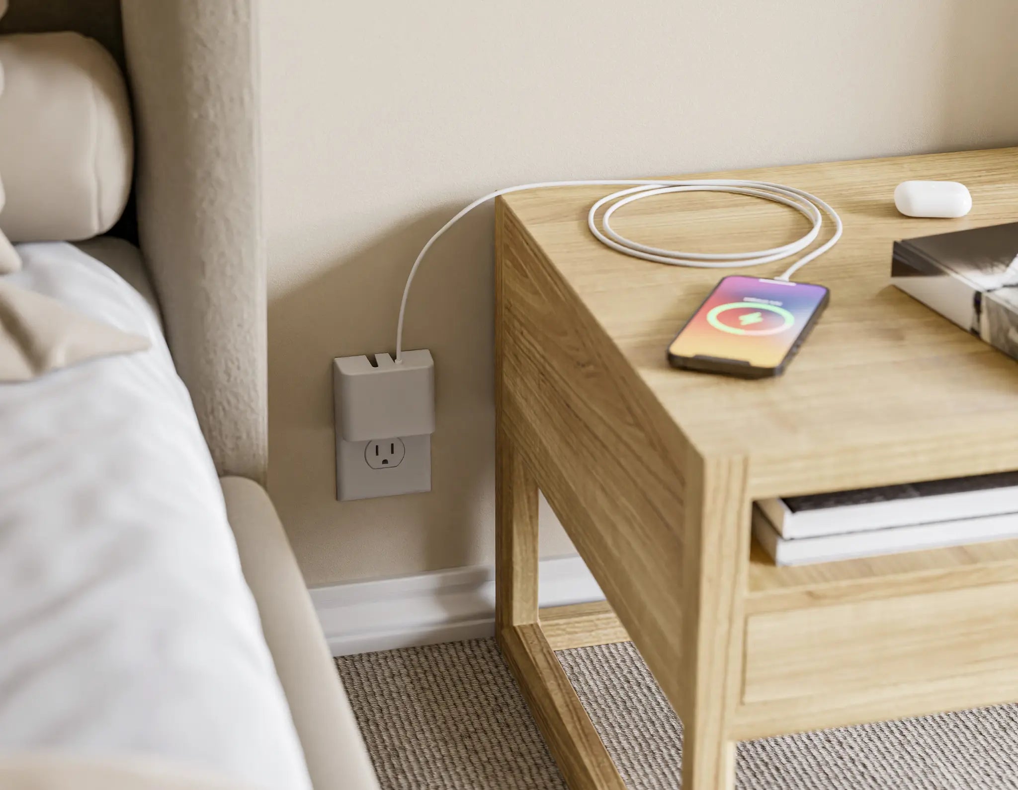 This image shows a bedroom setup with the Permaplug Charger Lock connected to a wall outlet near a wooden bedside table. The charger is powering a smartphone, which is wirelessly charging on the table, as well as a pair of wireless headphones placed next to it. The overall scene highlights a simple and organized charging solution in a cozy bedroom environment.