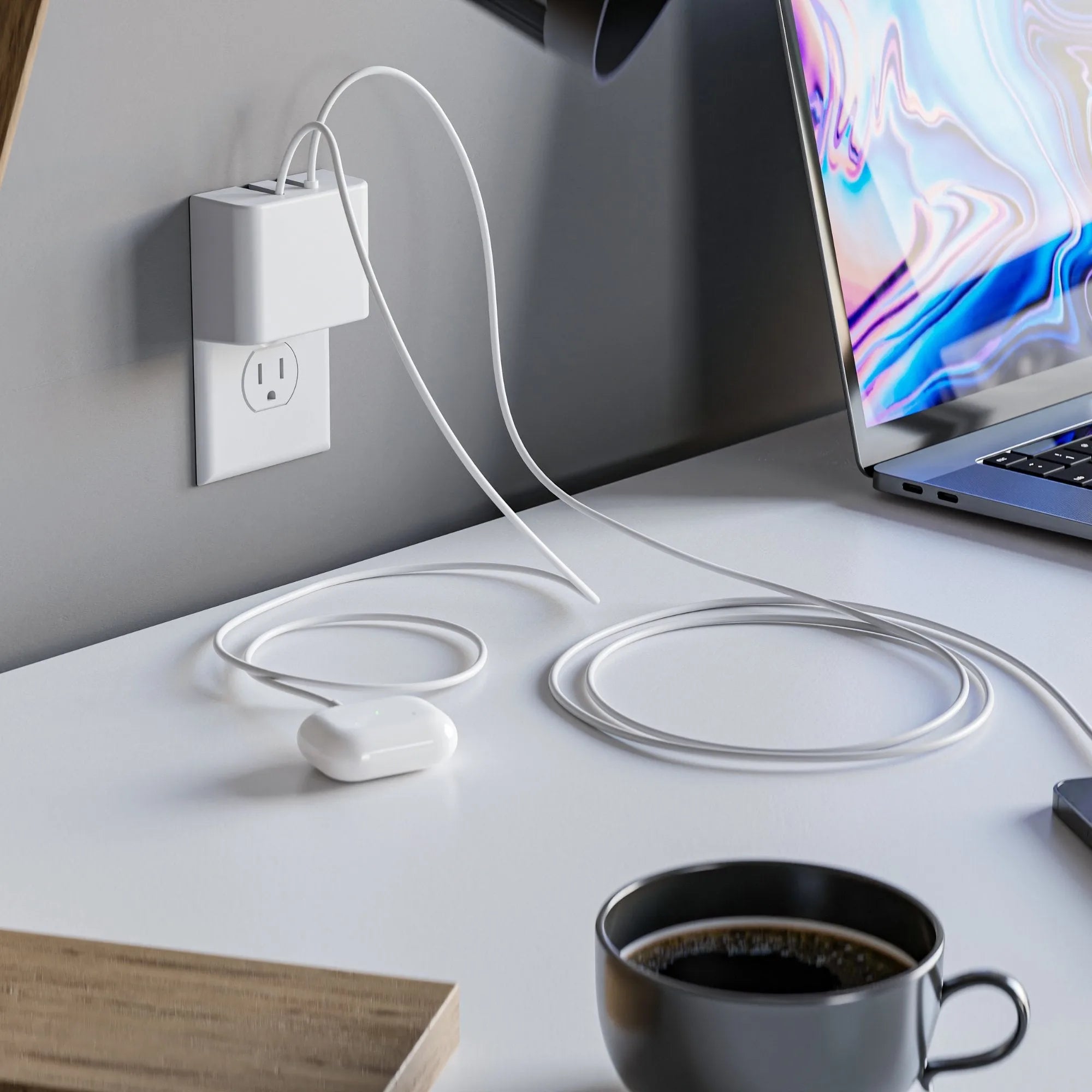 This image shows a minimalist workspace featuring the Permaplug Charger Lock securely plugged into a wall outlet. It has two cables attached, one charging a smartphone wirelessly on the desk and the other connected to a pair of wireless headphones. A MacBook Pro is also on the desk, alongside a cup of coffee and a wooden desk lamp, highlighting a clean and organized tech setup.